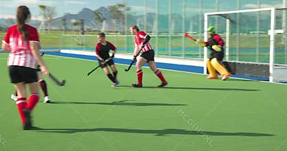 Female hockey players competing intensely on outdoor field, showcasing teamwork