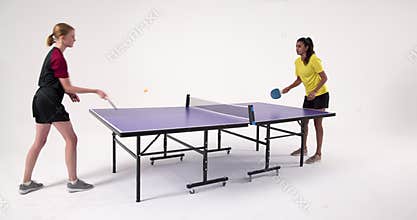 Playing table tennis, two women competing intensely in studio setting
