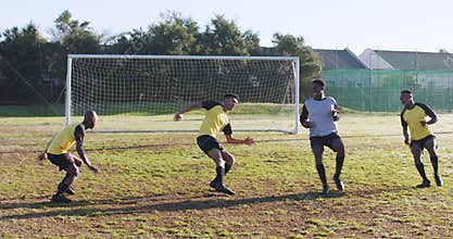 Playing soccer on field, men competing and defending near goalpost