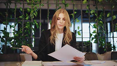 A professional woman in a modern office setting surrounded by vibrant indoor plants, embodying a perfect blend of