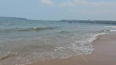 Miramar Beach is a popular beach in Panjim, Goa, A serene beach scene with gentle waves lapping against the sandy shore,