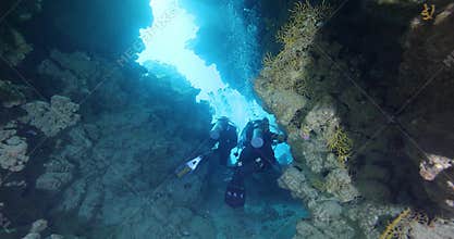 Silhouette of a scuba divers swimming in an underwater cave. A divers explores underwater cave ecosystems