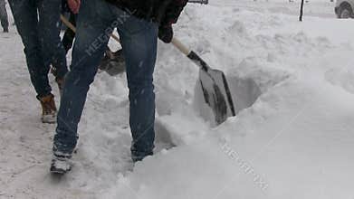 People with shovels clear snow from sidewalks