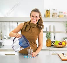 Housewife pouring water into glass from water filter pitcher