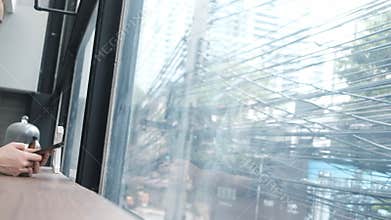 Thoughtful Woman Using Smartphone by Window in Urban Cafe with messy electric wires background