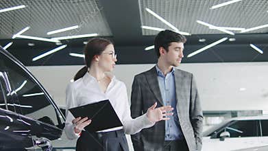 Car dealership staff assist customer in selecting vehicle during busy afternoon, showcasing new models and options