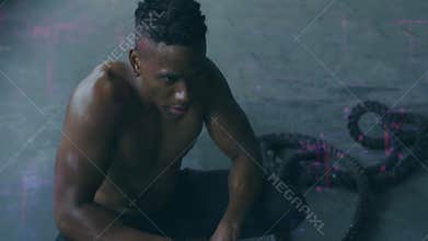 Crouching on floor, shirtless man with short hair appearing focused and determined
