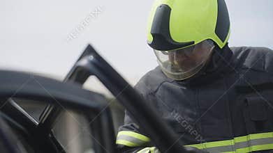 A courageous firefighter, equipped with specialized tools, heroically rescues people trapped in a car accident