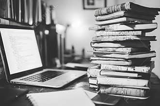 Stacked Books and Laptop on Desk, Black and White Photography