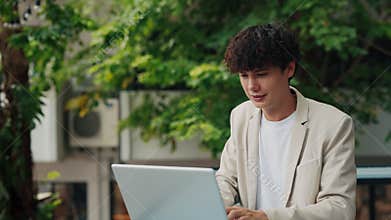 Portrait of curly haired man entrepreneur working on laptop in city downtown