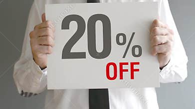 Salesman holding sale tag with twenty percent sales discount price. Consumerism concept.