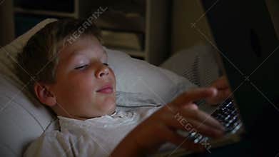 Boy Using Laptop Computer In Bed At Night
