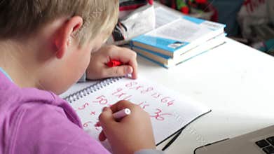 Boy Doing Math's Homework In Bedroom