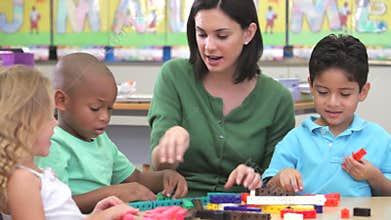 Teacher Sits With Group Of Children Using Construction Kit