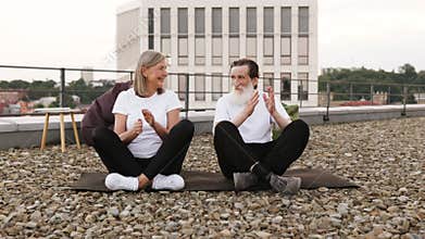 Older couple practicing yoga together on an urban rooftop