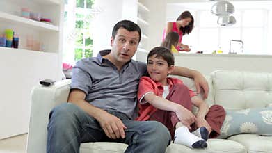 Hispanic Family Sitting On Sofa Watching TV Together