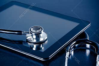 Medical stethoscope on modern digital tablet pc in laboratory on wood table