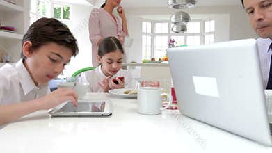 Family Using Digital Devices At Breakfast Table