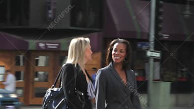 Two Businesswomen Chatting Walking Along Street