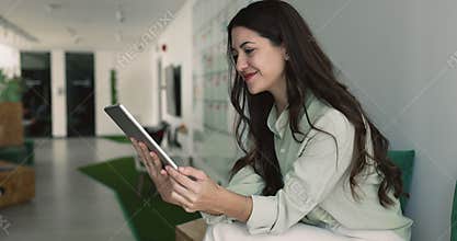 Positive beautiful young professional woman using online product on tablet