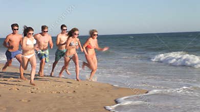 Group of teenagers run along beach