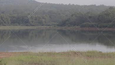Tropical view of Water reservoir with mountain in background.