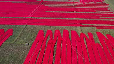 Aerial view of Hundreds of meters of newly dyed, bright red cotton are rolled out to dry in the sun in Narsingdi, Bangladesh.