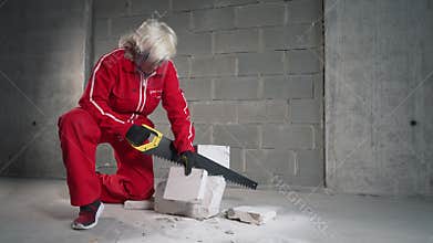 A woman cuts a foam concrete block into pieces.