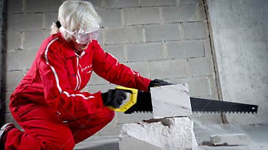 A woman finishes cutting brick blocks.
