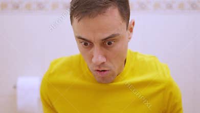 Man suffering from diarrhea using toilet paper in bathroom. Funny