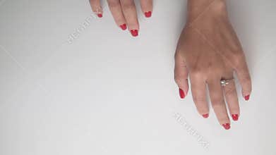 Video shows closeups of a womans hands with red nails and rings