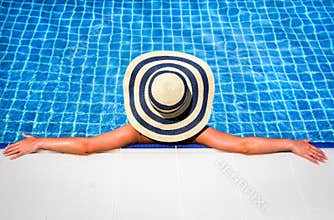 Woman in straw hat relaxing swimming pool