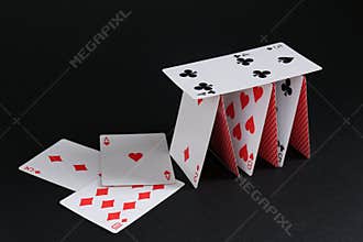 Collapsed house of playing cards on black background