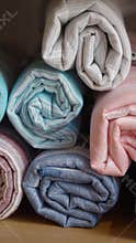 Stacked rolled fabrics in various colors displayed neatly