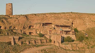 Aerial view of an Orthodox monk walking in remote cave monastery complex carved into cliffs, symbolizing spiritual devotion,