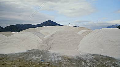 Dry salt heaps stored near large open quarry under cloudy sky aerial view