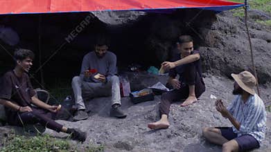 Moment as a model and companions, three South Asians and one East Asian, gathering beneath a tarp