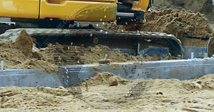 Bucket pressing into sand under pressure, digging trench, dumping scooped soil, leveling base
