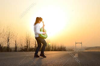 In the evening, girl playing guitar on the road