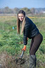 The girl plants trees on a field full of grass. afforestation campaign in Europe.