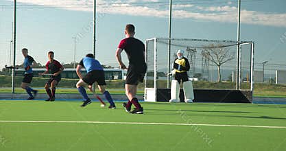 Playing field hockey, male athletes competing in intense match on green field