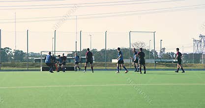 Playing field hockey, men competing in outdoor match on green field