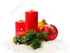 Red candles and fir branches and Christmas balls in snow
