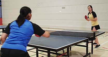 Playing table tennis, two women competing in indoor sports facility