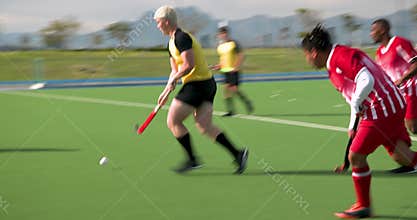 Playing field hockey, male athletes competing in intense match outdoors
