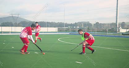 Playing field hockey, men competing intensely on outdoor sports field