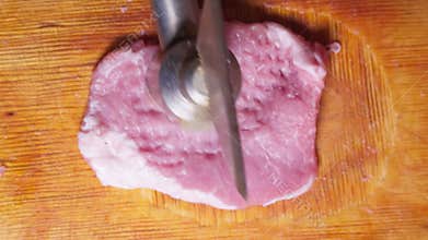 Cooking meat chop. Hit piece of meat with hammer. Top view.