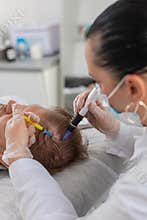 Trichologist doing man hair regeneration procedure dermapen microneedling vitamin exosomes injection
