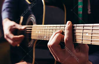 Man playing music at black wooden acoustic guitar