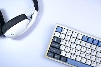 White keyboard with blue and dark keycaps, and headphones, top-down view, suggesting a digital workspace setup.